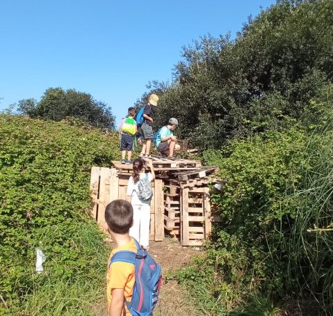 unos niños trepan sobre unos palets de madera que tapa el camino,